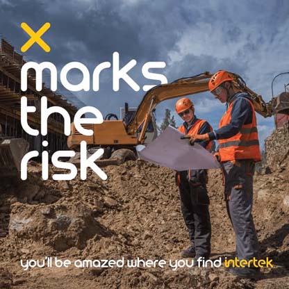 Two construction workers reviewing plans while standing near an excavator